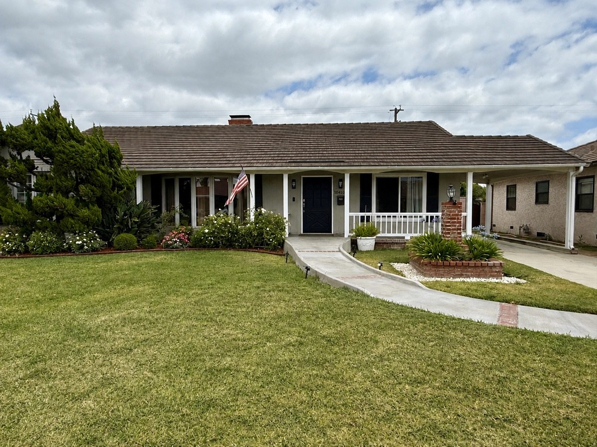 The front of Bellman House: a single-story home with a covered porch, white railings, an American flag and a ramp to the front door